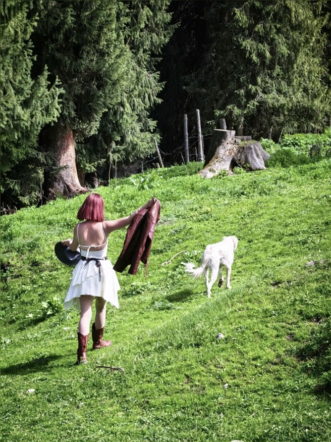 Hannah walking through a green forest clearing with a dog