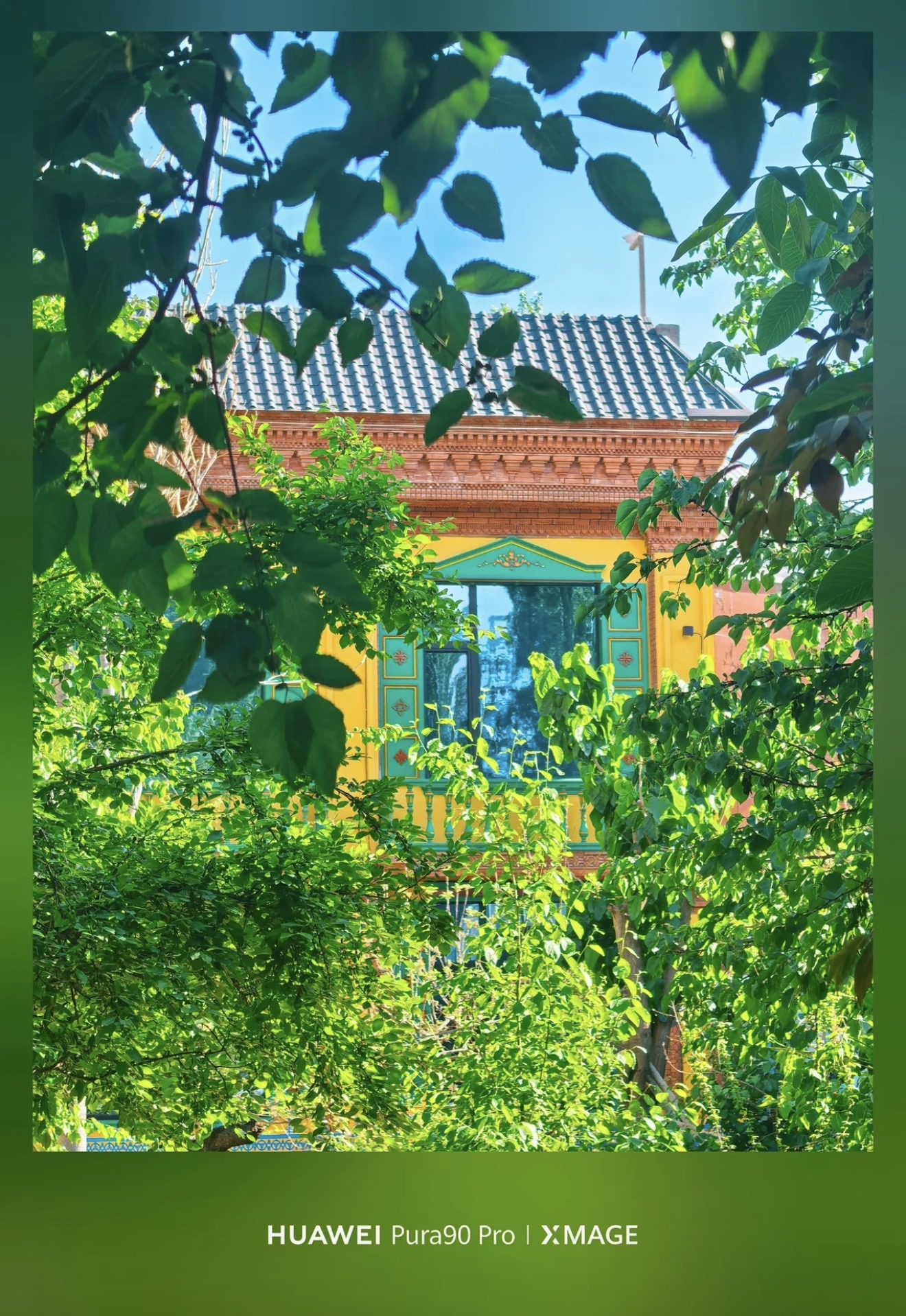A colourful Yili house framed by dense green leaves